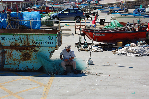 A fisherman fixes his net in Baiona
